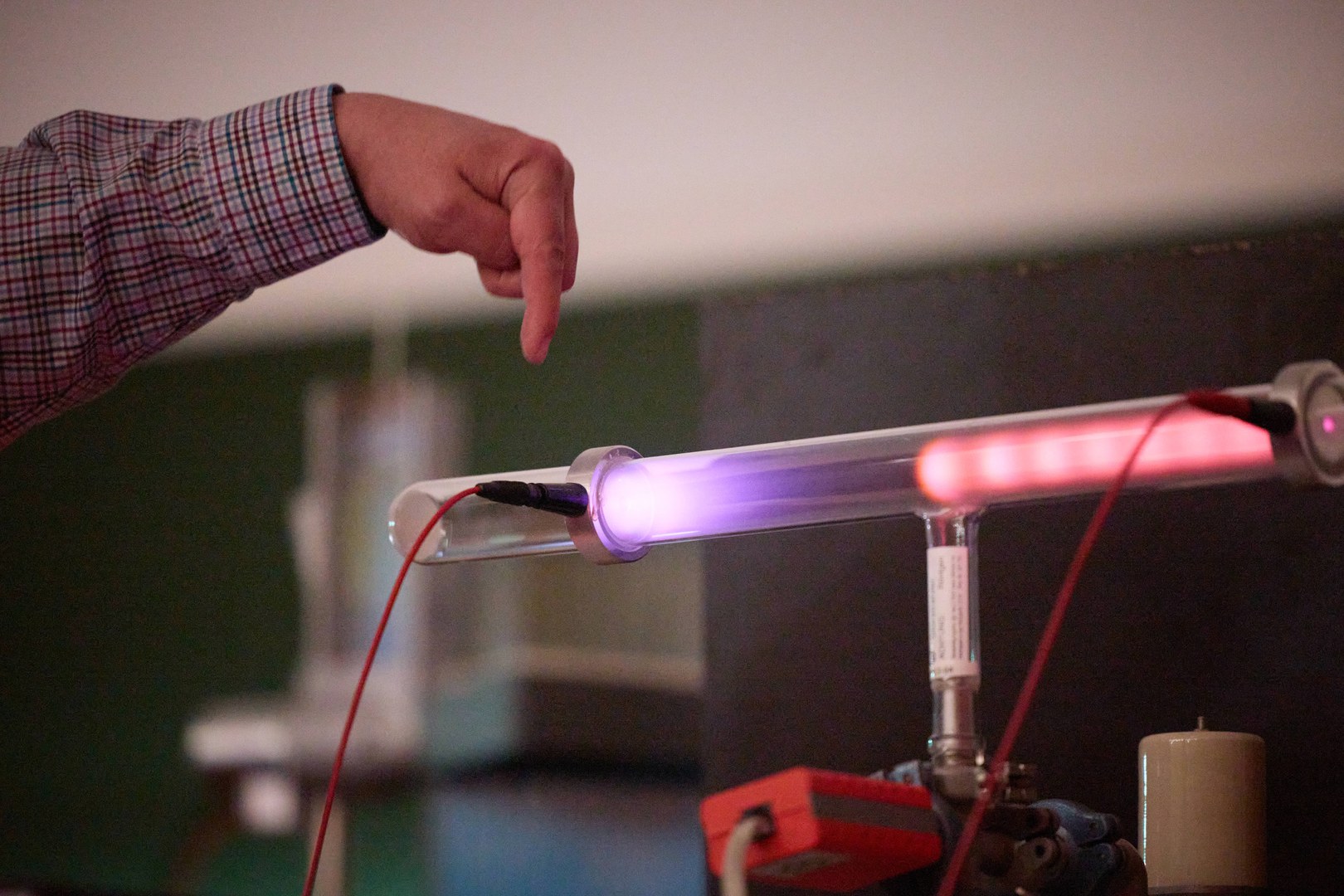 A voltage is applied and the gas atoms in the tube light up. The color of the light reveals which gas it is.