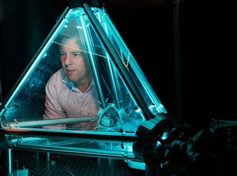 Prof. Dr. Simon Stellmer of the Physikalisches Institut at the University of Bonn stands behind a ring laser, which serves as a development platform for portable sensors.